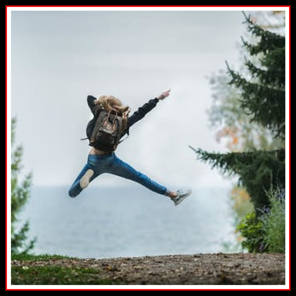 Happy Woman jumping for joy while wearing a long-sleeve t-shirt and a backpack