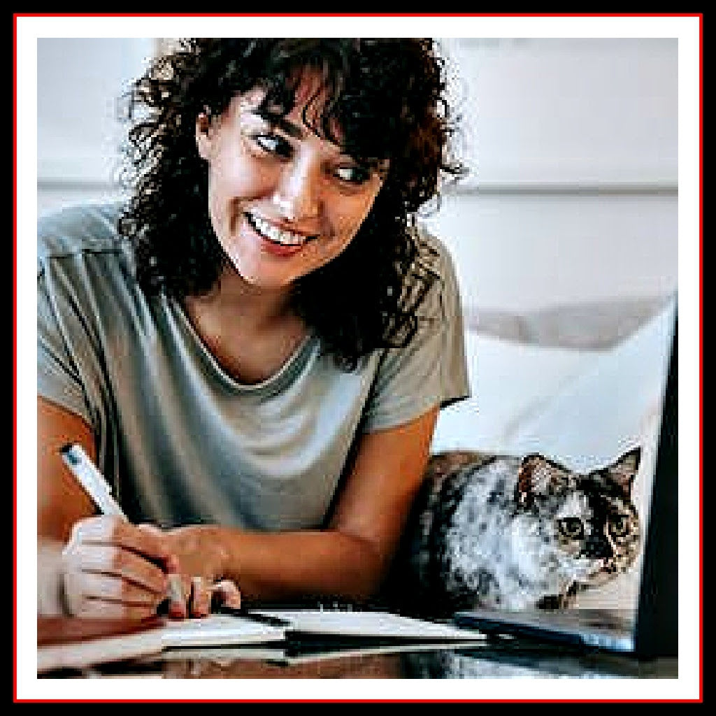 Photo of a woman and her cat looking at her laptop screen and taking notes