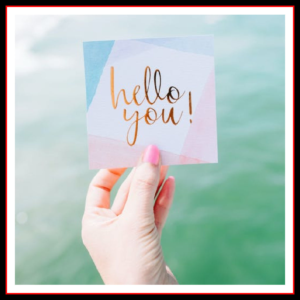 Photo of a women's hand holding a note card with text that reads: "hello you!"