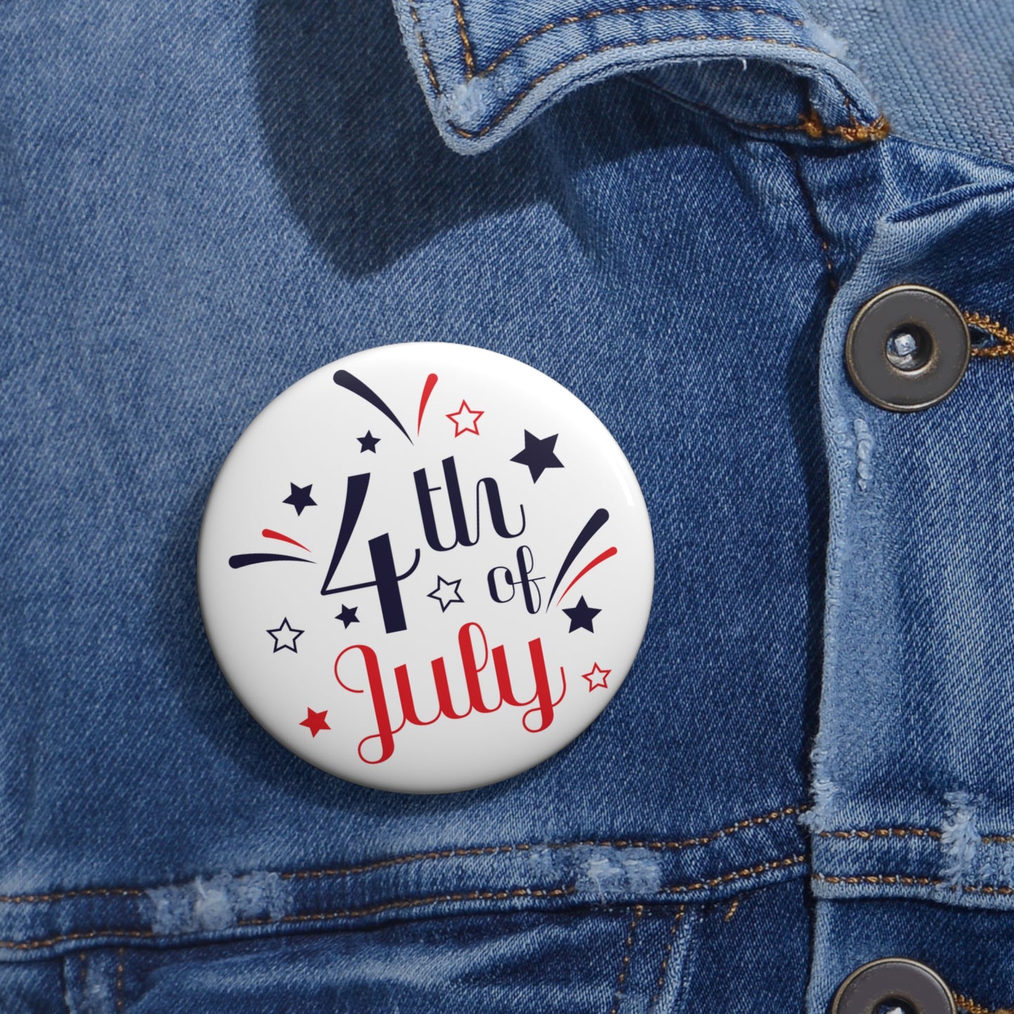 A colorful Printify 4th of July Button: Lightweight metal, featuring the text "4th of July" in red and blue is attached to a blue denim jacket.