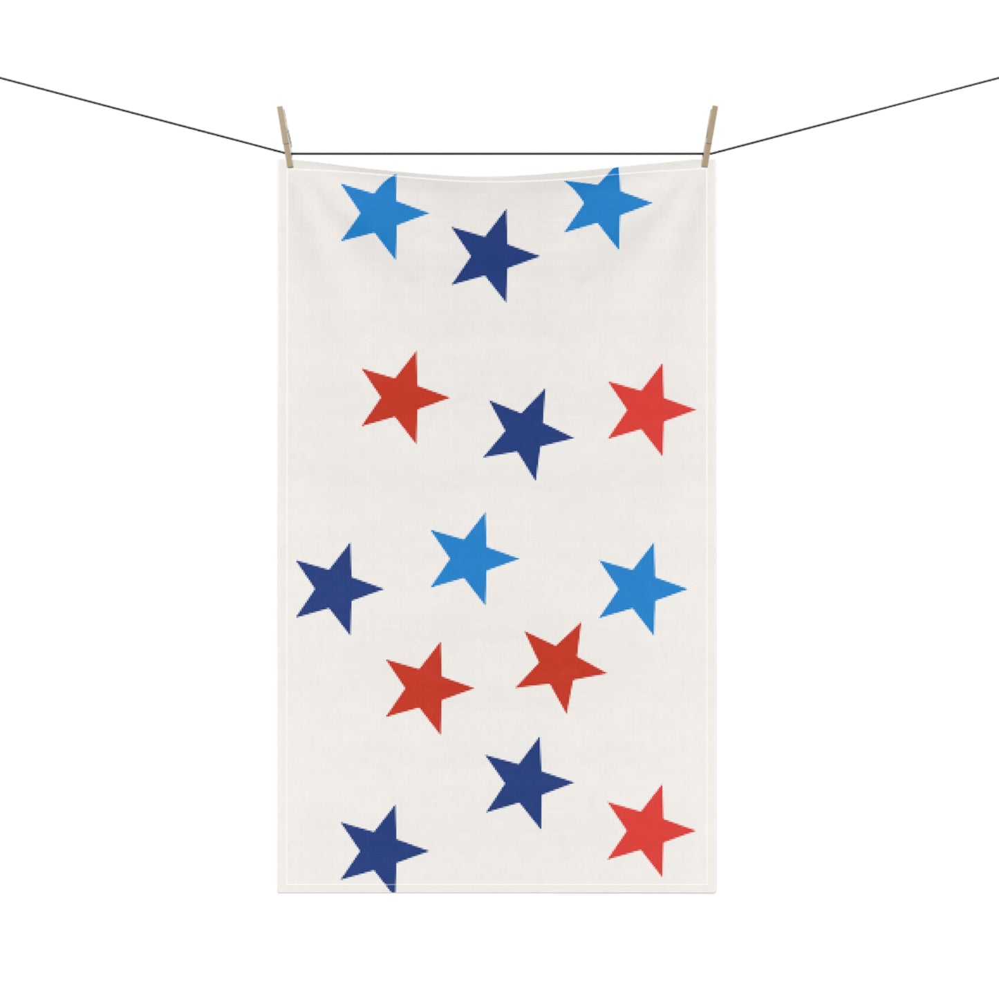An American-made, absorbent white cloth with red and blue Patriotic-Stars Kitchen Towel: Unisex; Cotton twill; 18"x30" by Printify hangs on a clothesline, secured with wooden clothespins.