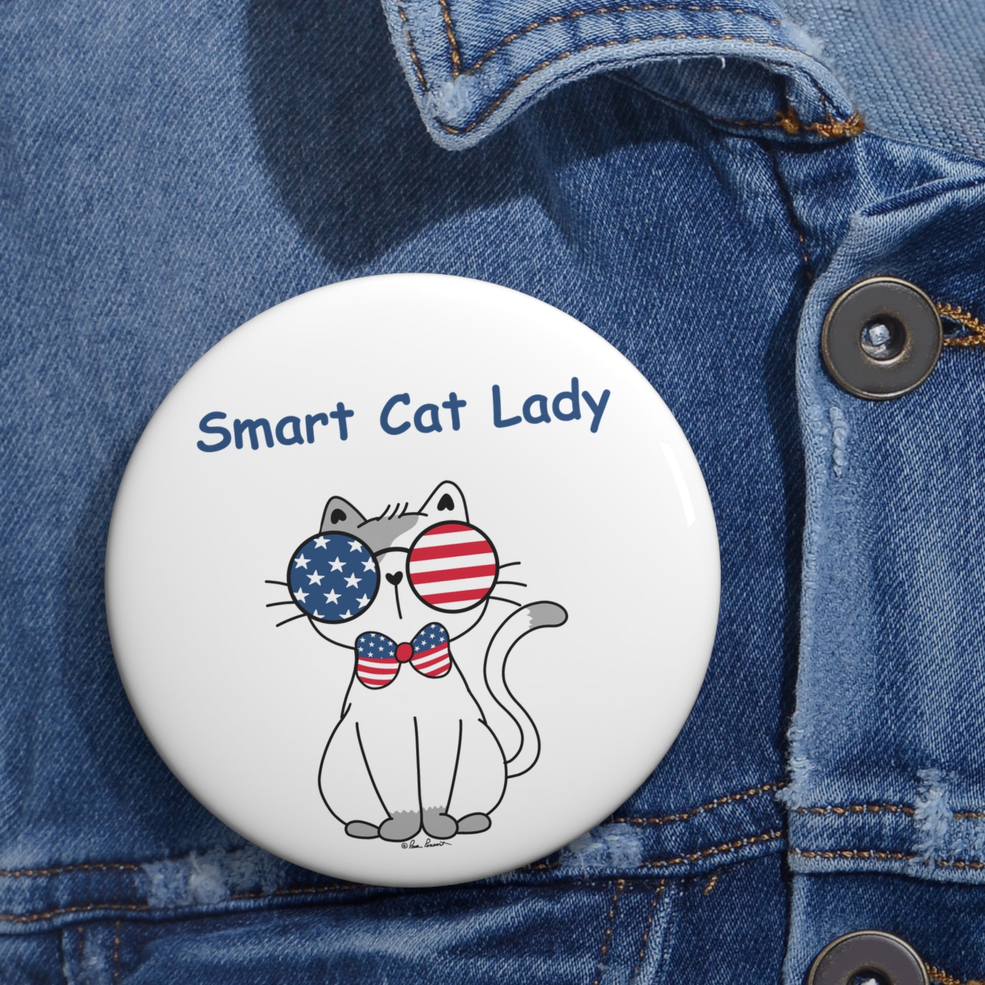 A whimsical accessory by Printify, the Unisex Smart Cat-Lady Button is available in 2 sizes and features a cartoon cat wearing American flag sunglasses and a bow tie, complete with the text "Smart Cat Lady." Lightweight yet durable, this metal button perfectly complements any outfit when pinned to a denim jacket.