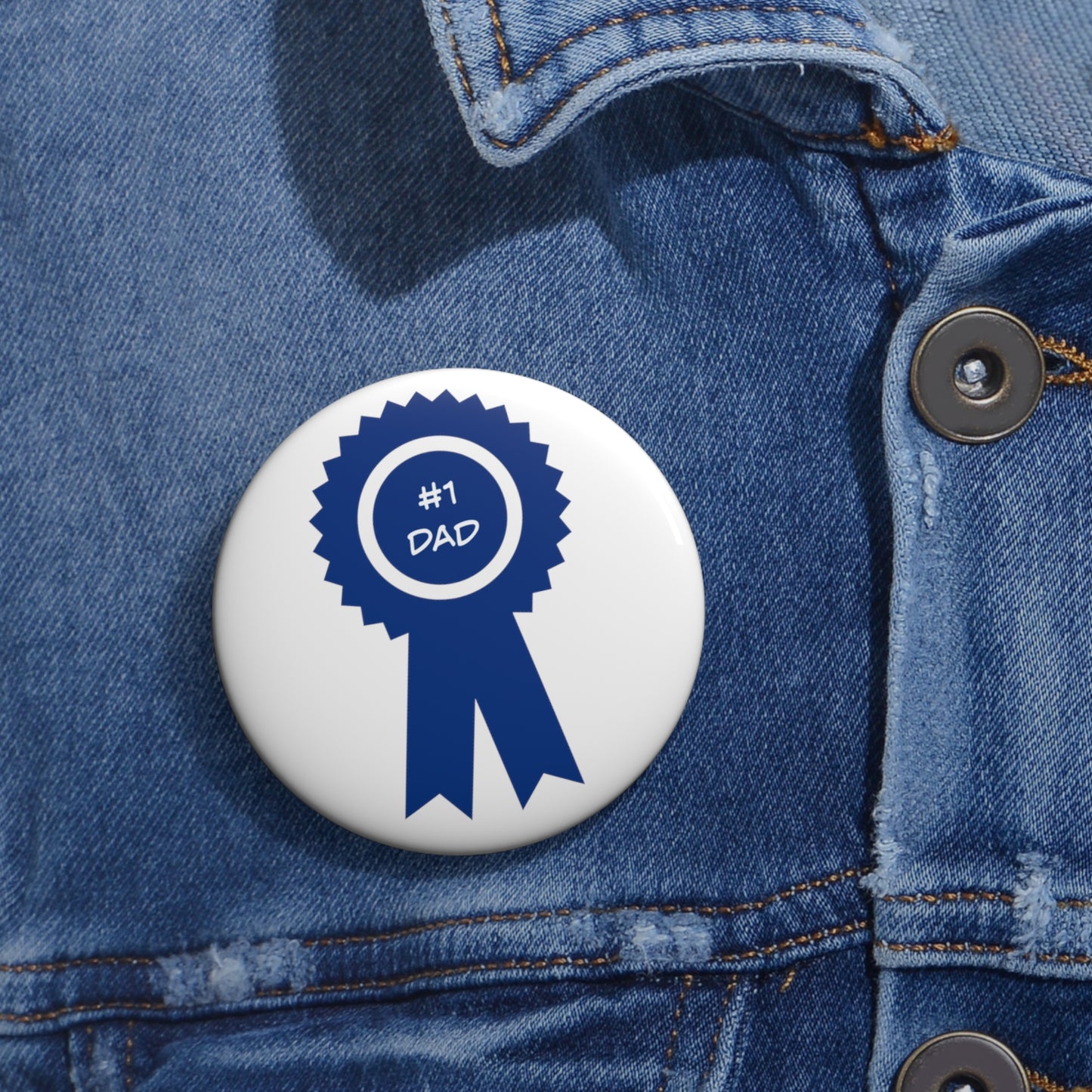 A blue ribbon badge with the text "#1 Dad" is pinned to a denim jacket using a #1 Dad Button: 2 sizes; Lightweight metal; Graphics from Printify.