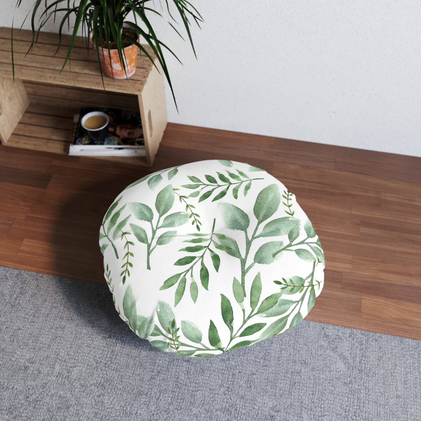 Printify round tufted floor pillow with a green botanical design on a wooden floor next to a potted plant and a coffee mug.
