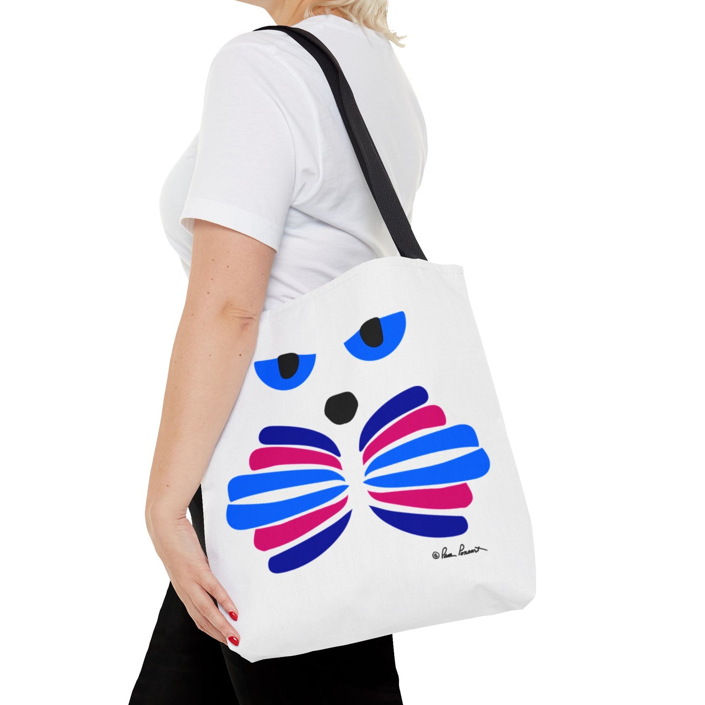 A person holding a stylish Printify Cat-Face Tote Bag, available in 3 sizes and made from durable polyester with a colorful abstract design, stands against their white shirt, appealing to cat lovers everywhere.