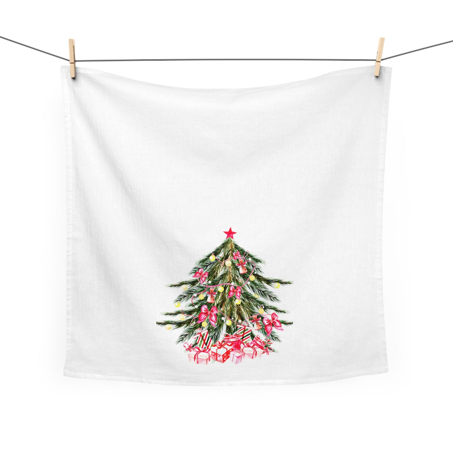 A Christmas-Tree Kitchen Towel by Printify, featuring a large 28" x 28" cotton design with a printed tree embellished with pink ribbons and gifts, hangs gracefully on a line with wooden clips. This exquisite piece adds a festive touch to your holiday décor.