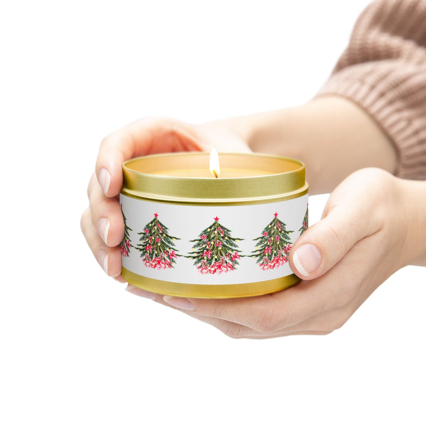 Hands gently cradle a glowing candle in a Printify Festive Christmas Tin-Candle, showcasing images of Christmas trees. Crafted from eco-friendly coconut soy wax, this reusable tin comes in two sizes with an Evergreen scent, adding a warm glow and sustainable charm to any holiday setting.