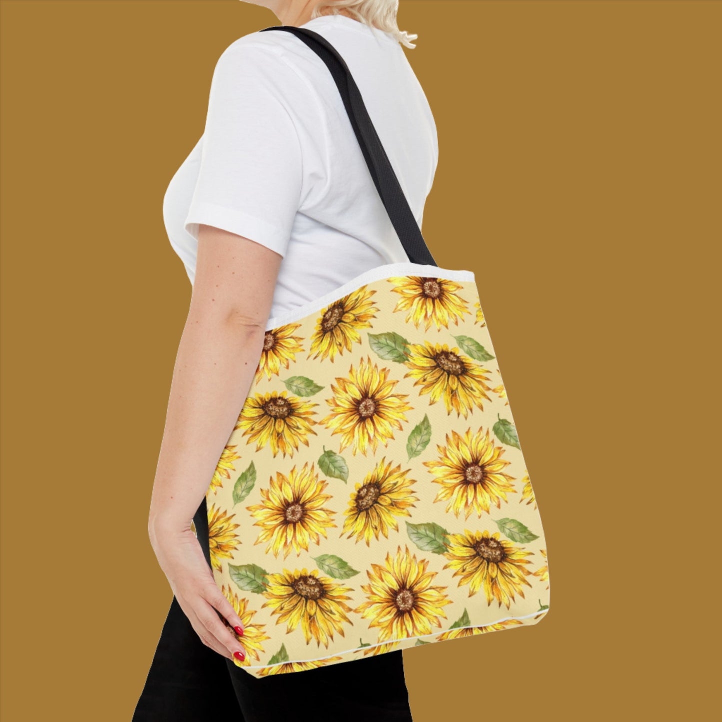 Woman in a white t-shirt carrying a medium Yellow Floral Tote Bag with a bright sunflower print, viewed from the side by Printify.