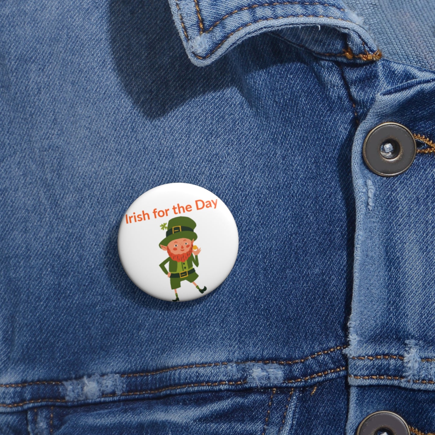 A Printify Irish-for-the-Day Pin Button (3 sizes) for St. Patrick's Day, featuring a cartoon leprechaun and "Irish for the Day" text, shown on a denim jacket.