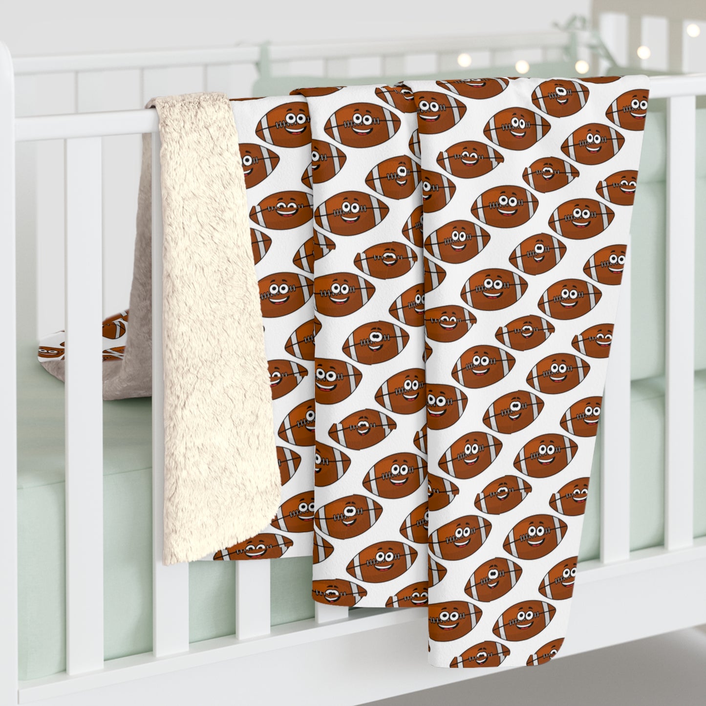 A Printify Happy Football-Faces Blanket made of Sherpa polyester in your choice of two sizes hangs over the side of a white crib, alongside a beige fluffy blanket and a white blanket with a subtle pattern—a perfect touch for little football fans.