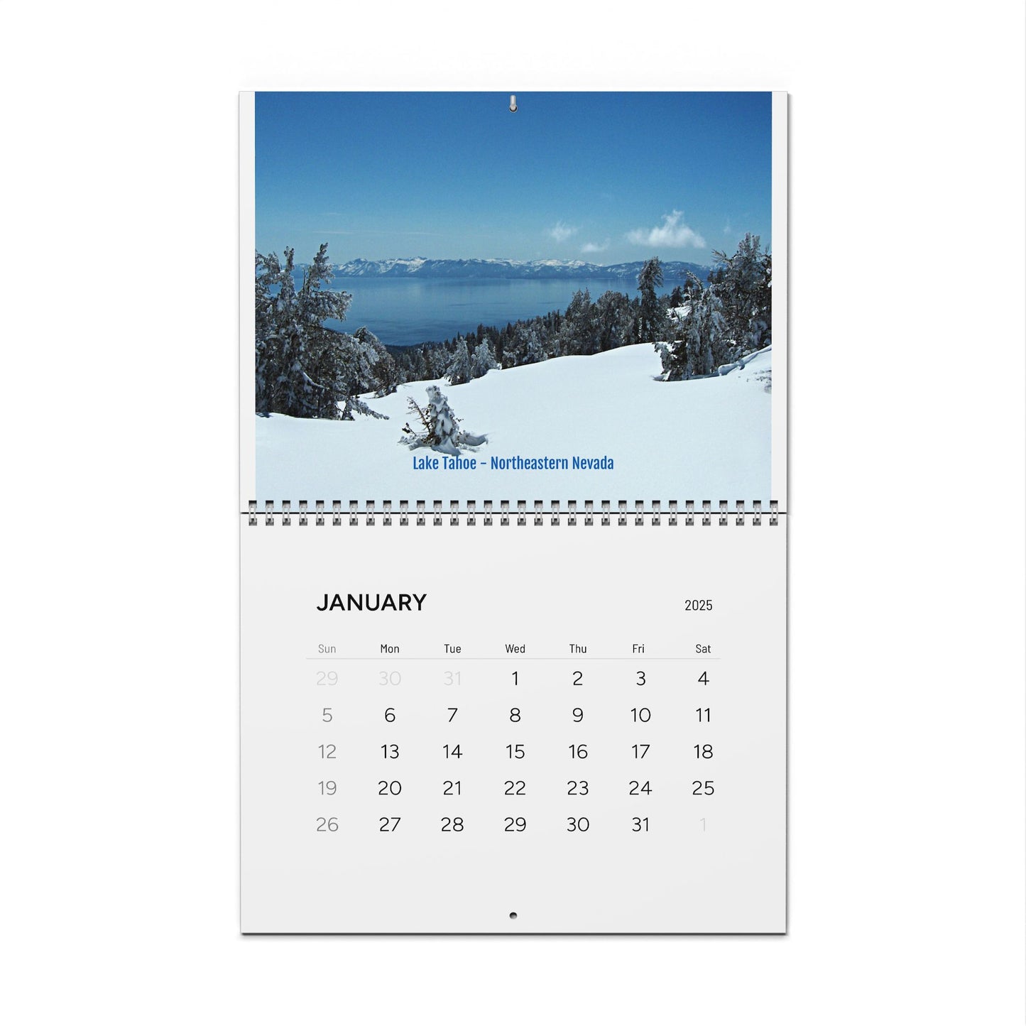 The Printify Minimalist 2025 Wall Calendar, open to January, showcases a snowy landscape with trees and Lake Tahoe in Northeastern Nevada, offering an inspirational view.