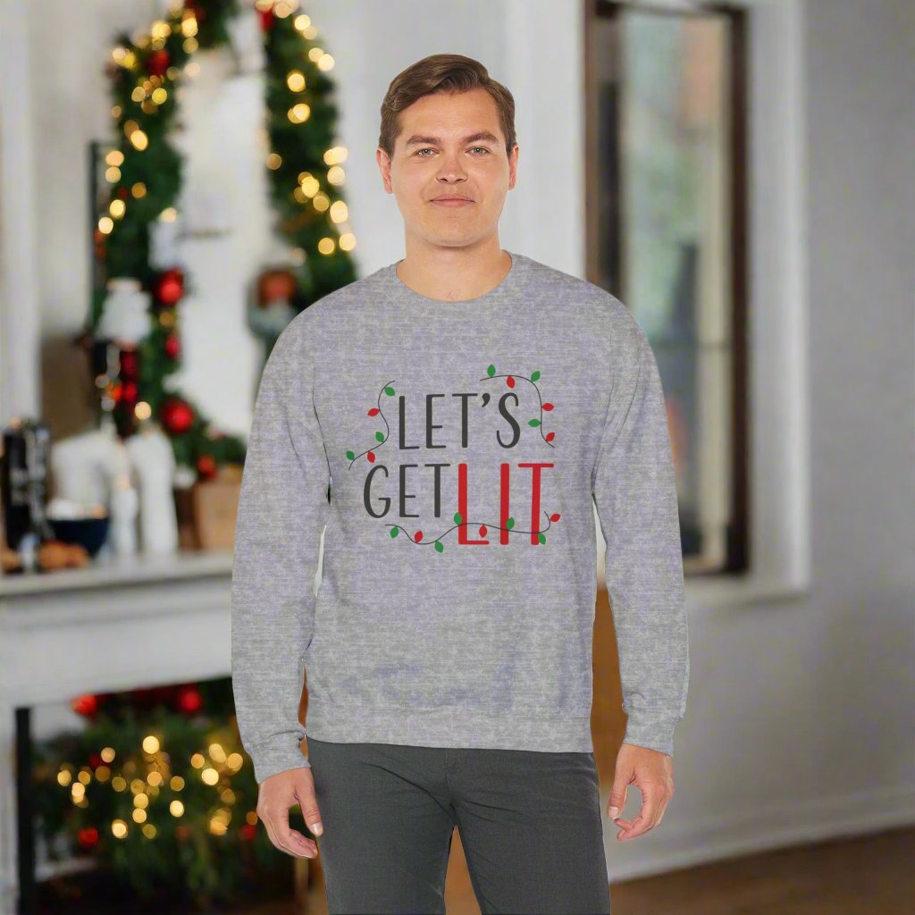 A person wearing a Printify Holiday Unisex Sweatshirt, featuring the Gildan brand's "Let's Get Lit" design, stands indoors enveloped in the cozy comfort of its medium-heavy fabric blend. Festive holiday decorations illuminate the background, creating a warm and cheerful atmosphere.