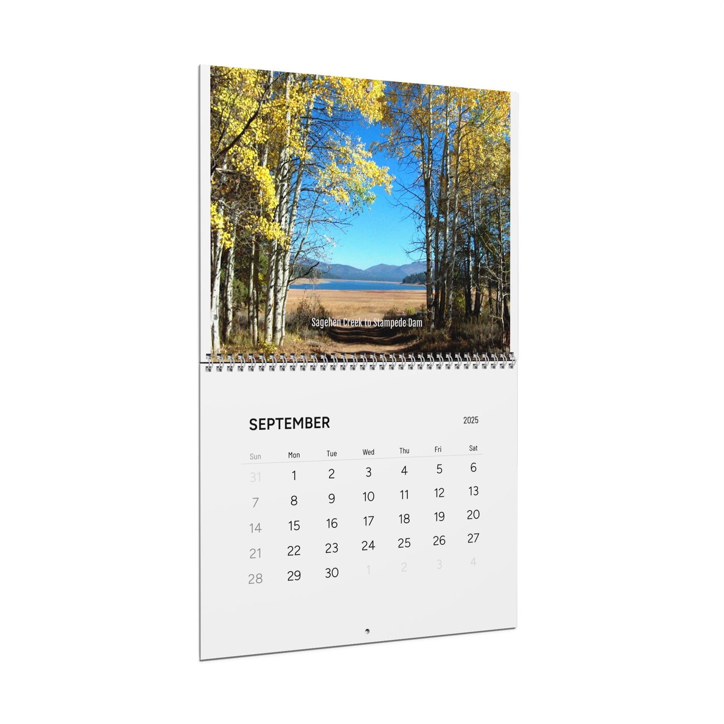The Minimalist 2025 Wall Calendar by Printify, open to September, features a landscape photo of yellow-leaved trees and a distant mountain beneath a blue sky, creating an inspirational atmosphere.