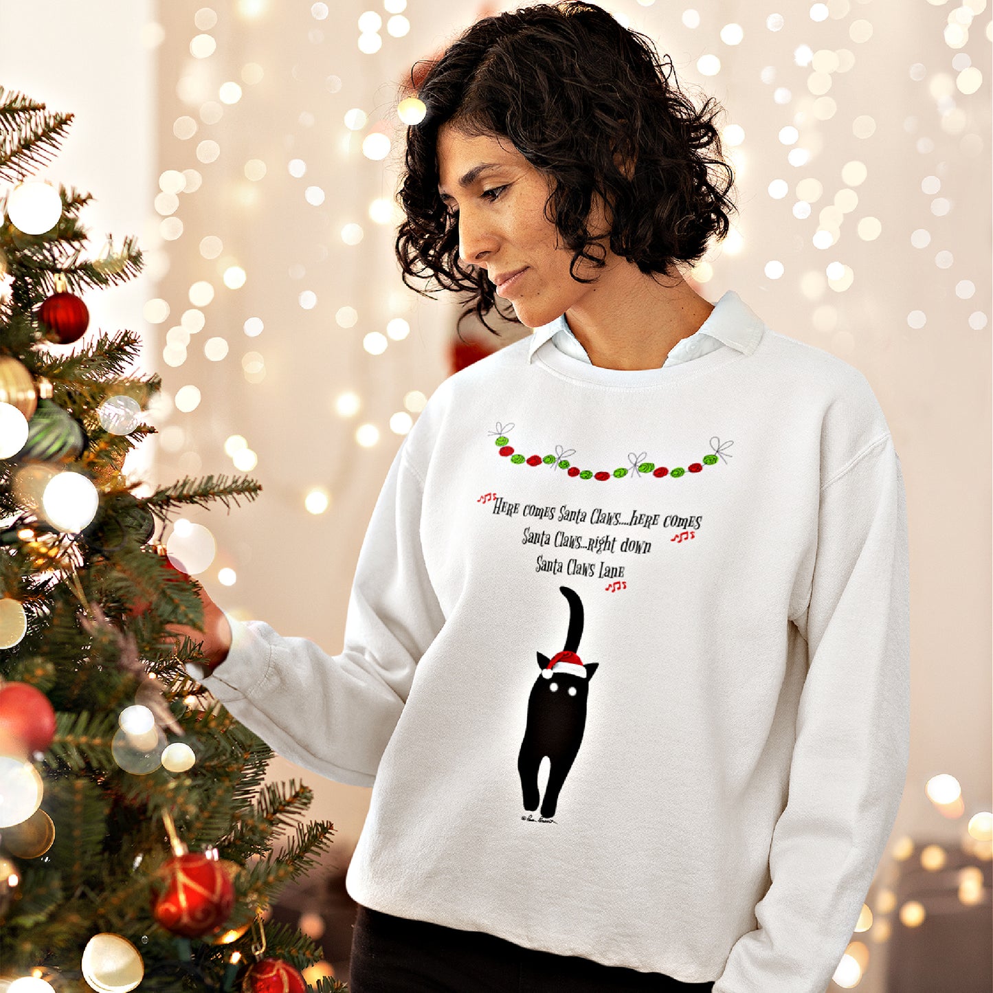 A person wearing a comfortable medium-heavy Santa Claws Sweatshirt from Printify decorates a Christmas tree. This festive unisex Gildan sweatshirt, available in three colors, showcases a white design featuring a black cat with a Santa hat and playful "Santa Claws" text, perfectly capturing the holiday season spirit.