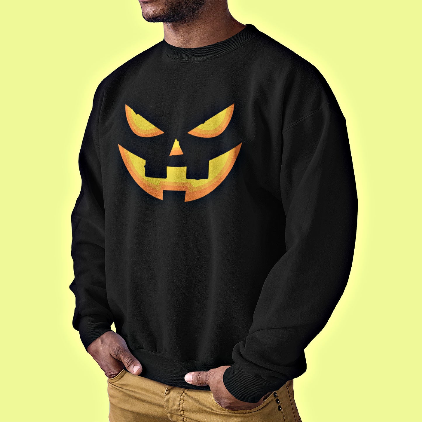 A man wearing our unisex Black Halloween Sweatshirt featuring a yellow-orange smiling Pumpkin Face