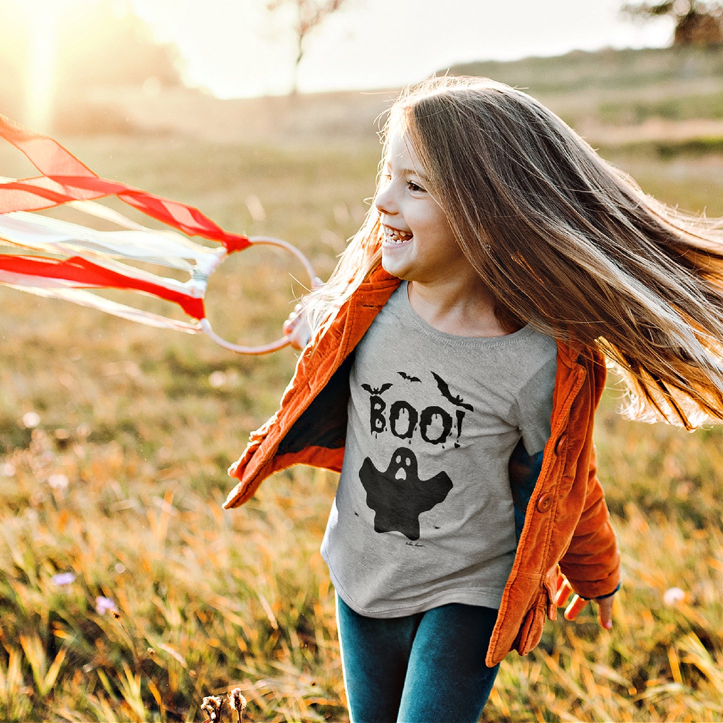 Mock up of a little girl playing in the countrywide while wearing our heather grey Kids Halloween T-shirt