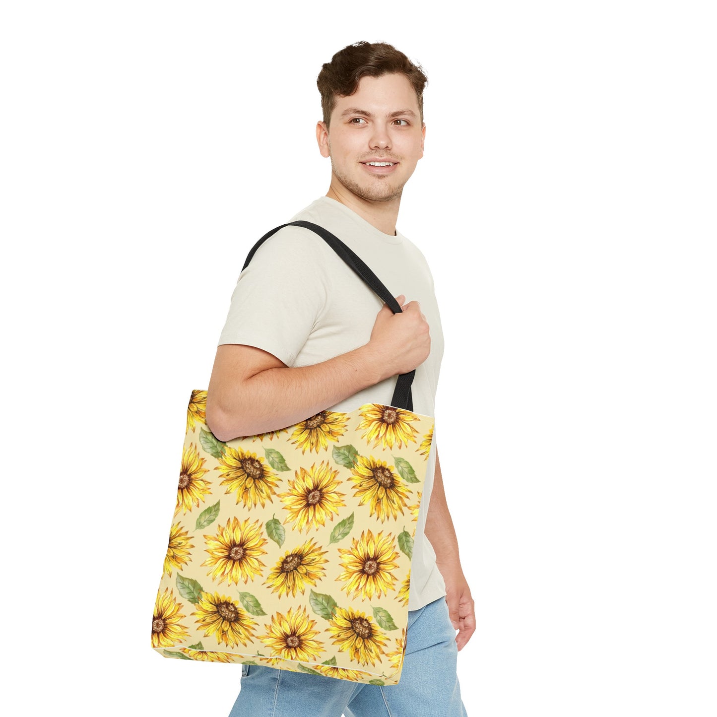 Man in a beige t-shirt and denim carrying a Printify Sunflowers Polyester Tote Bag over his shoulder, smiling at the camera, isolated on a white background.
