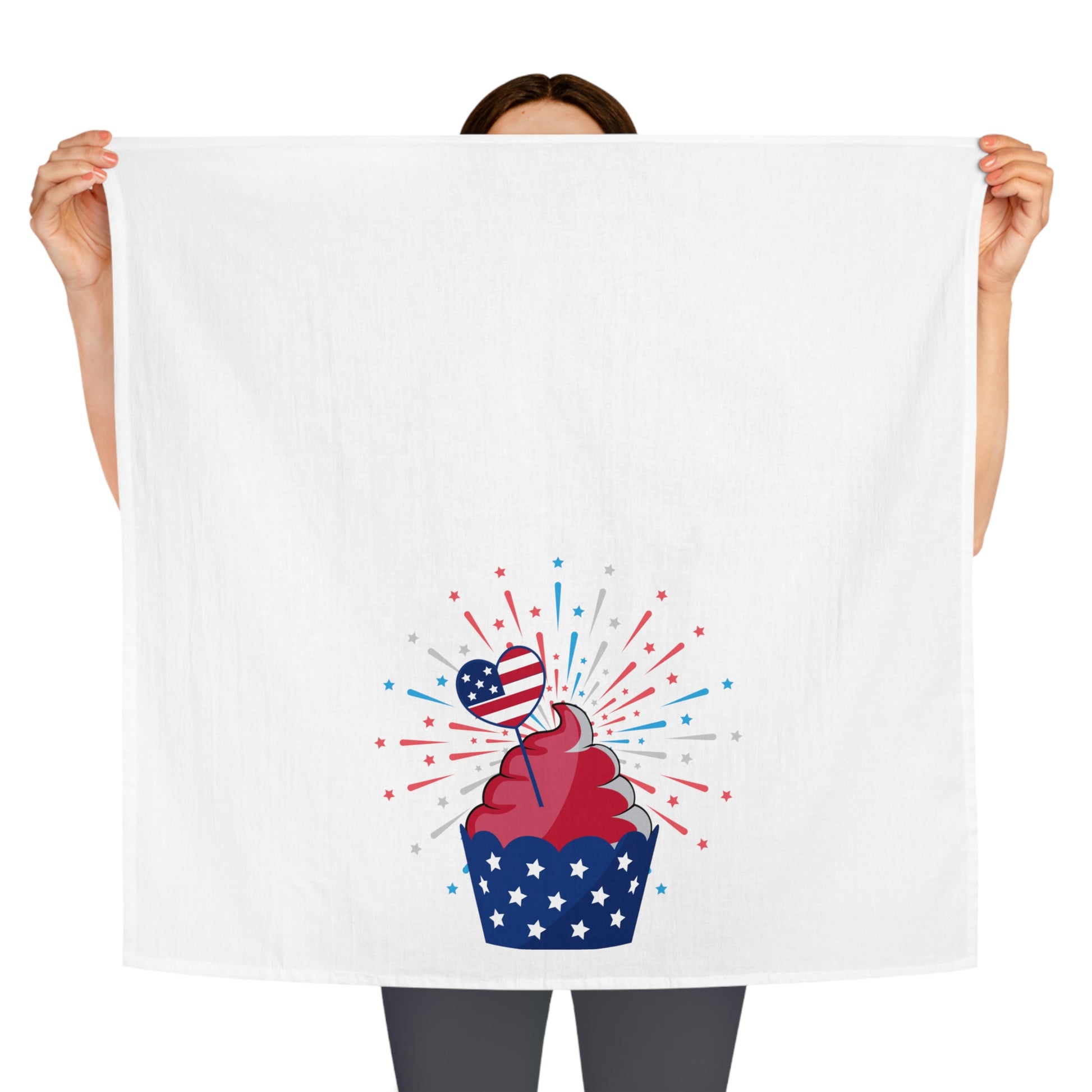 A person holding a Printify Decorative Kitchen Towel with a cupcake and fireworks, providing a festive touch to any setting.