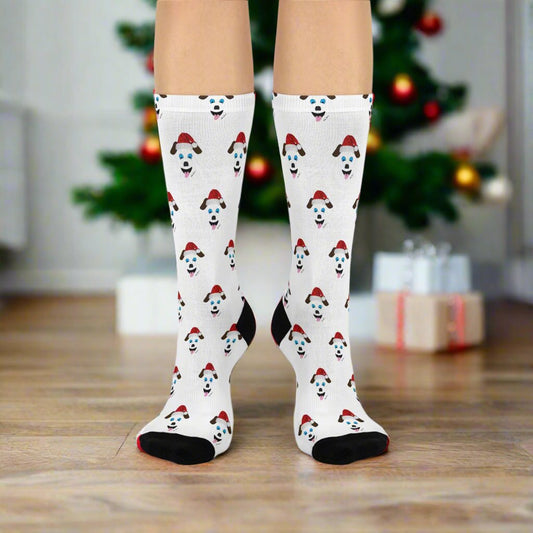 A person wearing Printify's Festive Santa-Dog Crew-Socks, designed for pet lovers and offering unmatched comfort, stands in front of a decorated Christmas tree, enhancing the charm of the holiday celebrations.