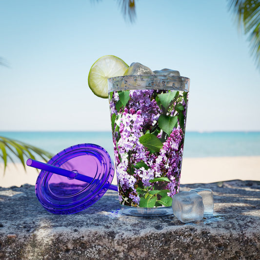 A Purple Lilacs Tumbler by Printify with ice and limes on a rock.