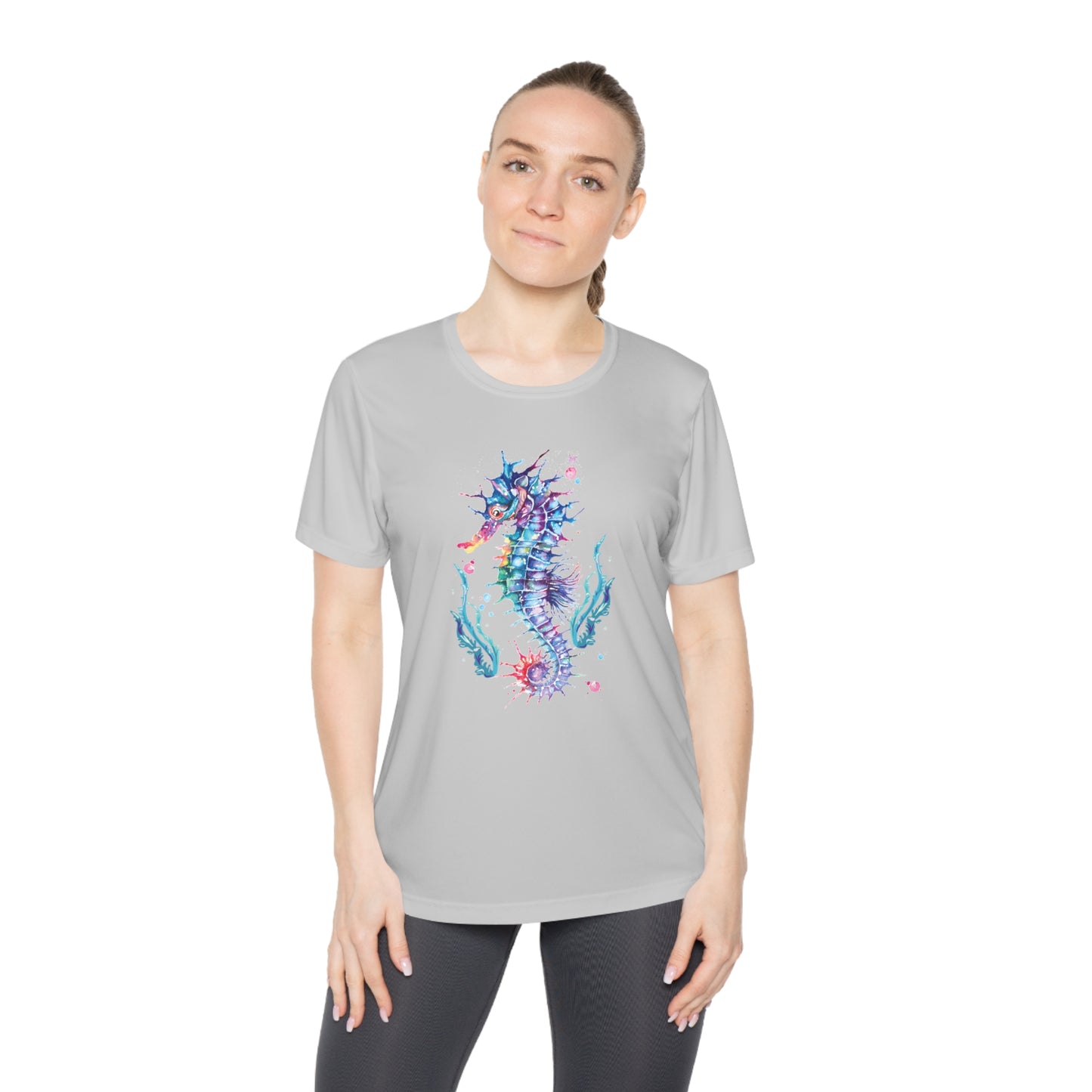 Person wearing a light gray Printify Moisture-wicking Ladies T-shirt: Seashorse; Sport Tek 350 with a colorful, abstract sea horse design and black pants, standing against a white background. Perfectly tailored for a feminine fit and featuring moisture-wicking fabric for added comfort.