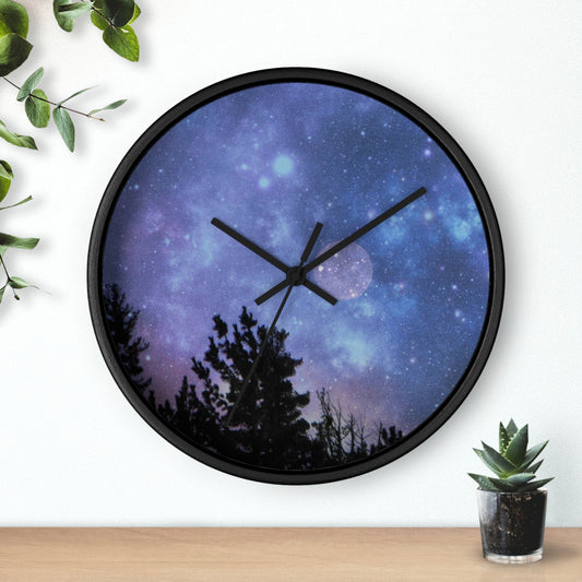 A Printify Blue-Moon Wall Clock with a galaxy and treeline design on its face, mounted on a wall near a potted plant.