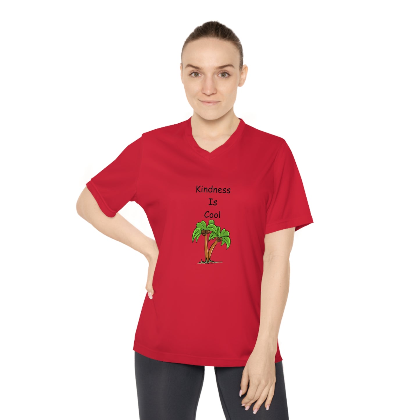 Standing with one hand on their hip, a person is wearing a Printify Women's Kindness-Is-Cool V-neck T-shirt from Team 365, featuring UV 40+ protection and a graphic of two palm trees.