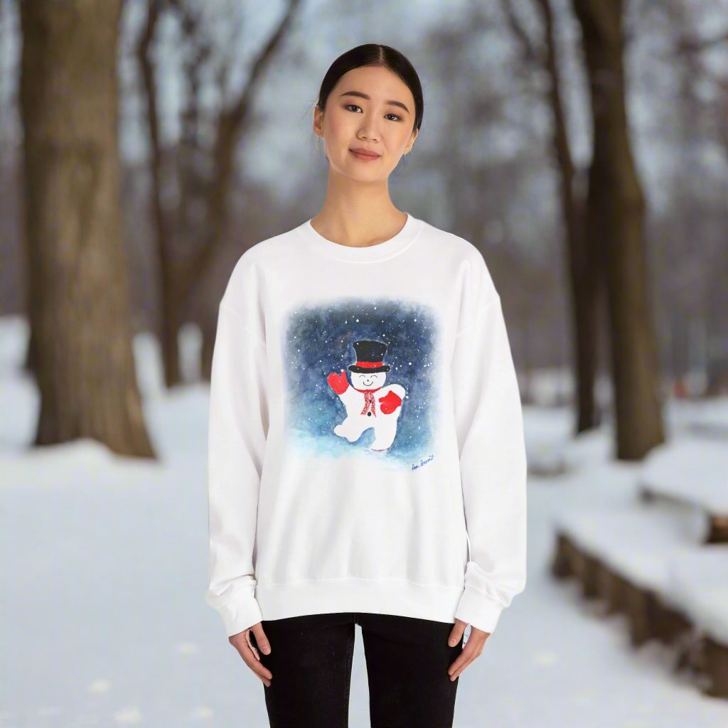 In a snowy park, a person is wrapped in the Charming Snowman Crewneck Sweatshirt from Printify. This unisex Gildan brand garment features a design reminiscent of a delicate watercolor painting, capturing the festive spirit with its playful snowman illustration set against a winter wonderland backdrop—perfect for holiday apparel.