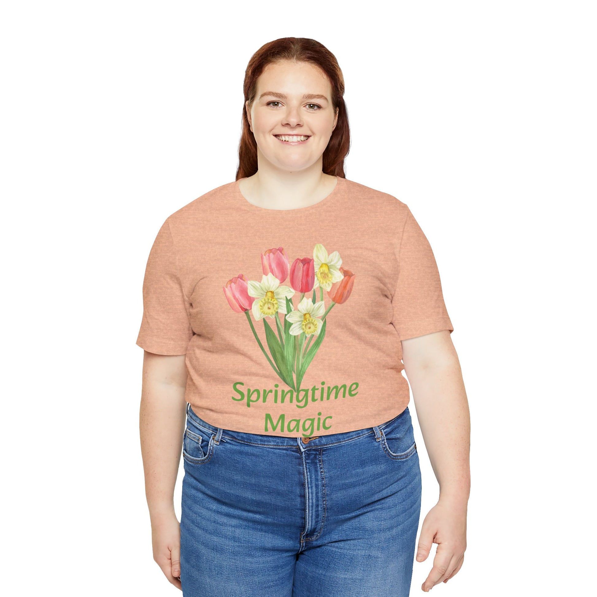 Woman in a brown Unisex Springtime-Magic T-shirt from Printify with graphic artistry and the words "springtime magic" paired with blue jeans, smiling at the camera.