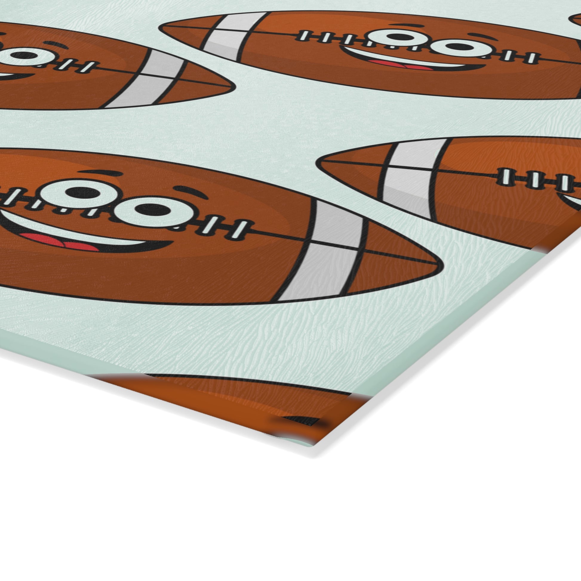 The Playful Football-Faces Cutting Board from Printify features smiling cartoon footballs with braces and white stripes on glass—a fun kitchen decor piece. Available in 2 sizes.