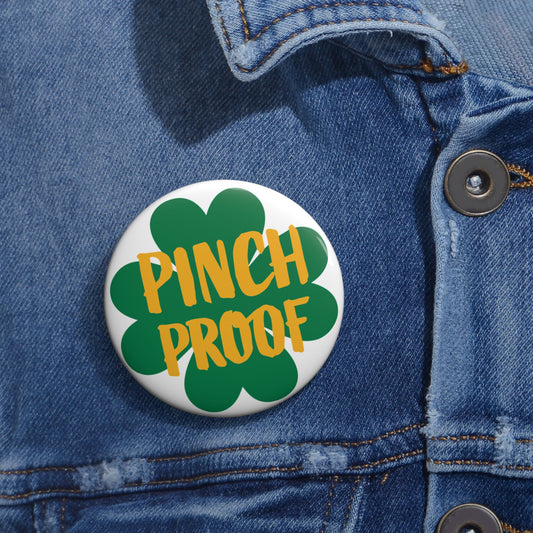 The Printify Metal Pin Button, available in 2 sizes, features a green shamrock and "Pinch Proof" text—an ideal unisex accessory for St. Patrick's Day, shown pinned to a blue denim jacket.