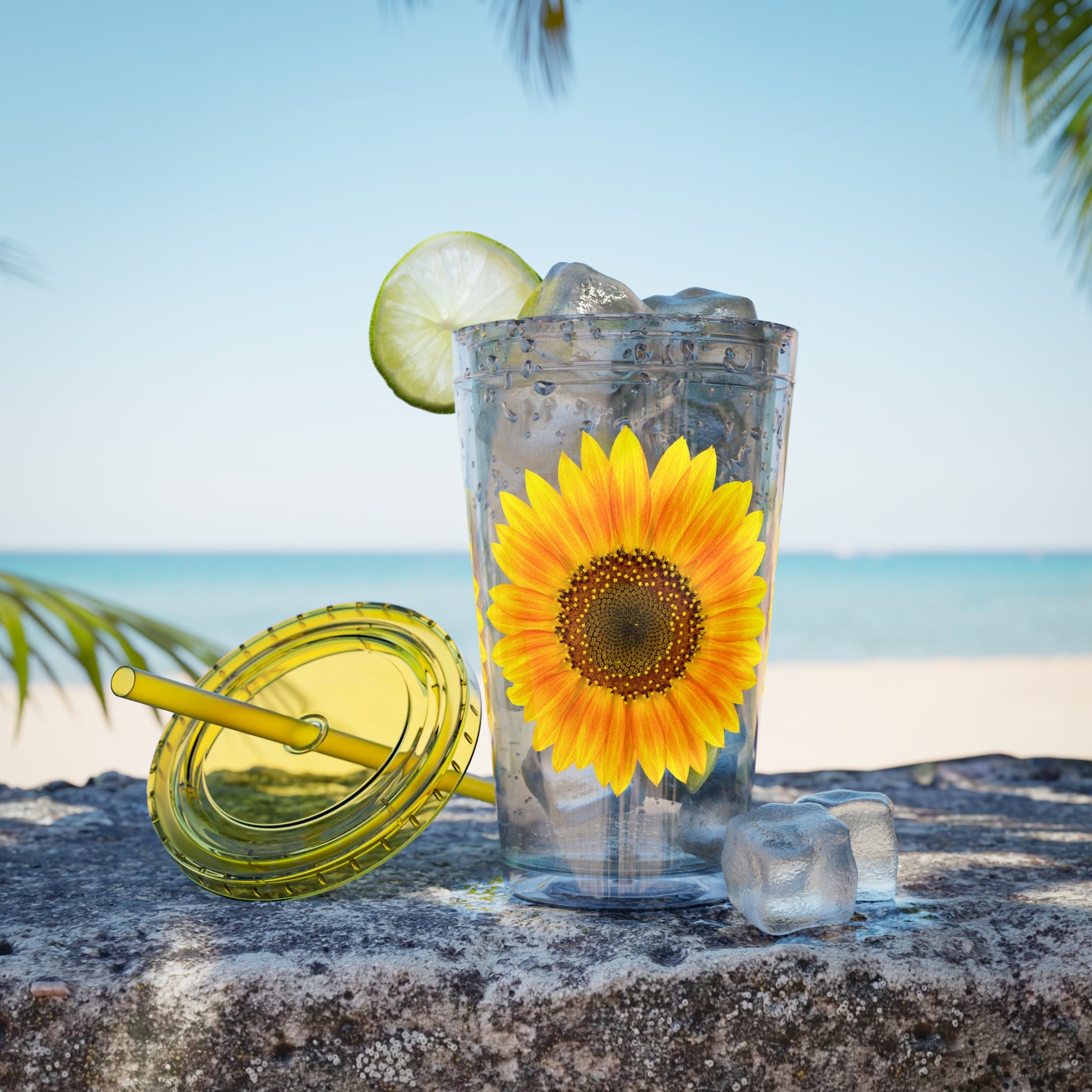 A Golden Sunflower Tumbler by Printify with ice and limes on a rock.