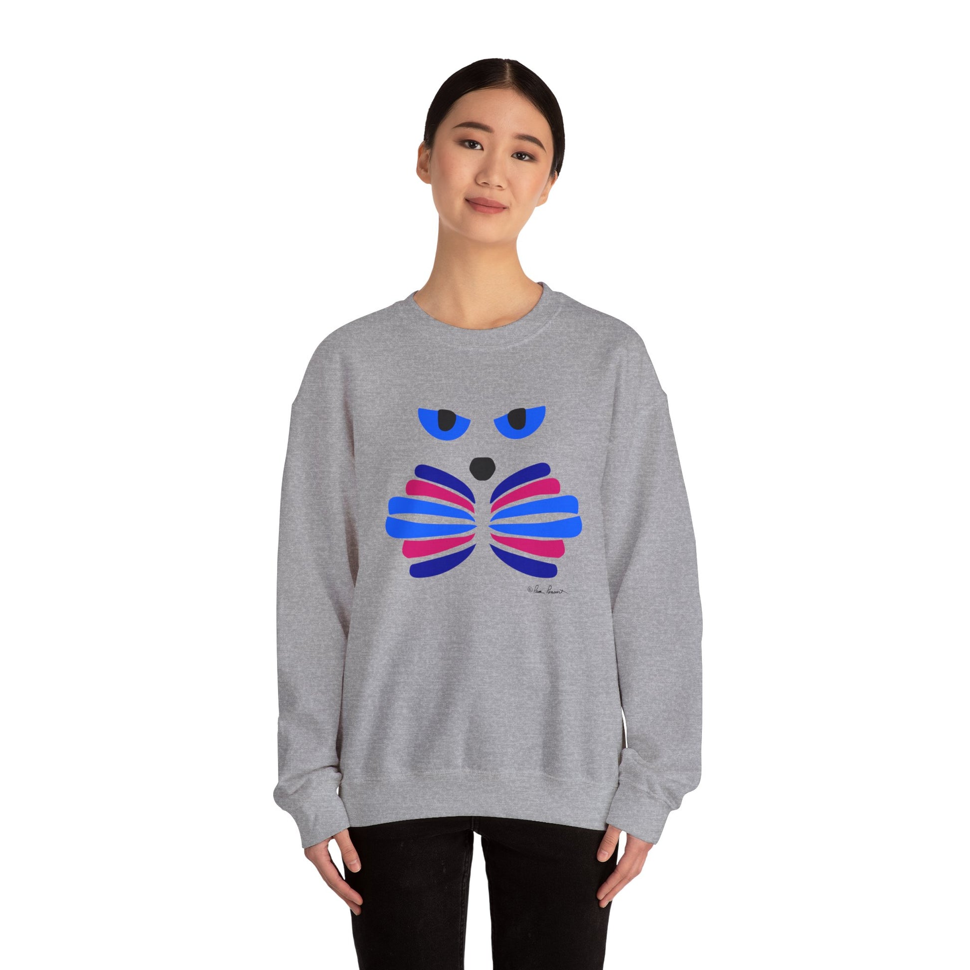 A person wears the Printify Whimsical Cat Graphic Sweatshirt, a unisex crewneck featuring an artistic cat design with an abstract face and bow tie in blue, pink, and purple.