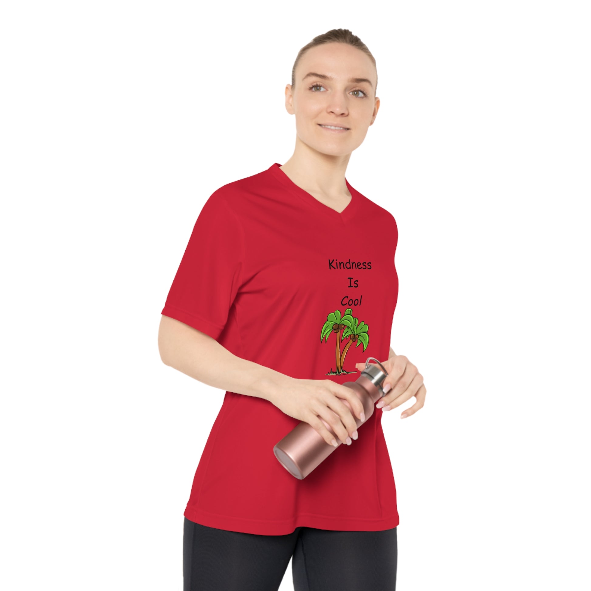 A woman in a Printify Women’s Kindness-Is-Cool Team 365 V-neck T-shirt with UV 40+ protection, featuring a palm tree illustration and made of moisture-wicking polyester, holds a water bottle.