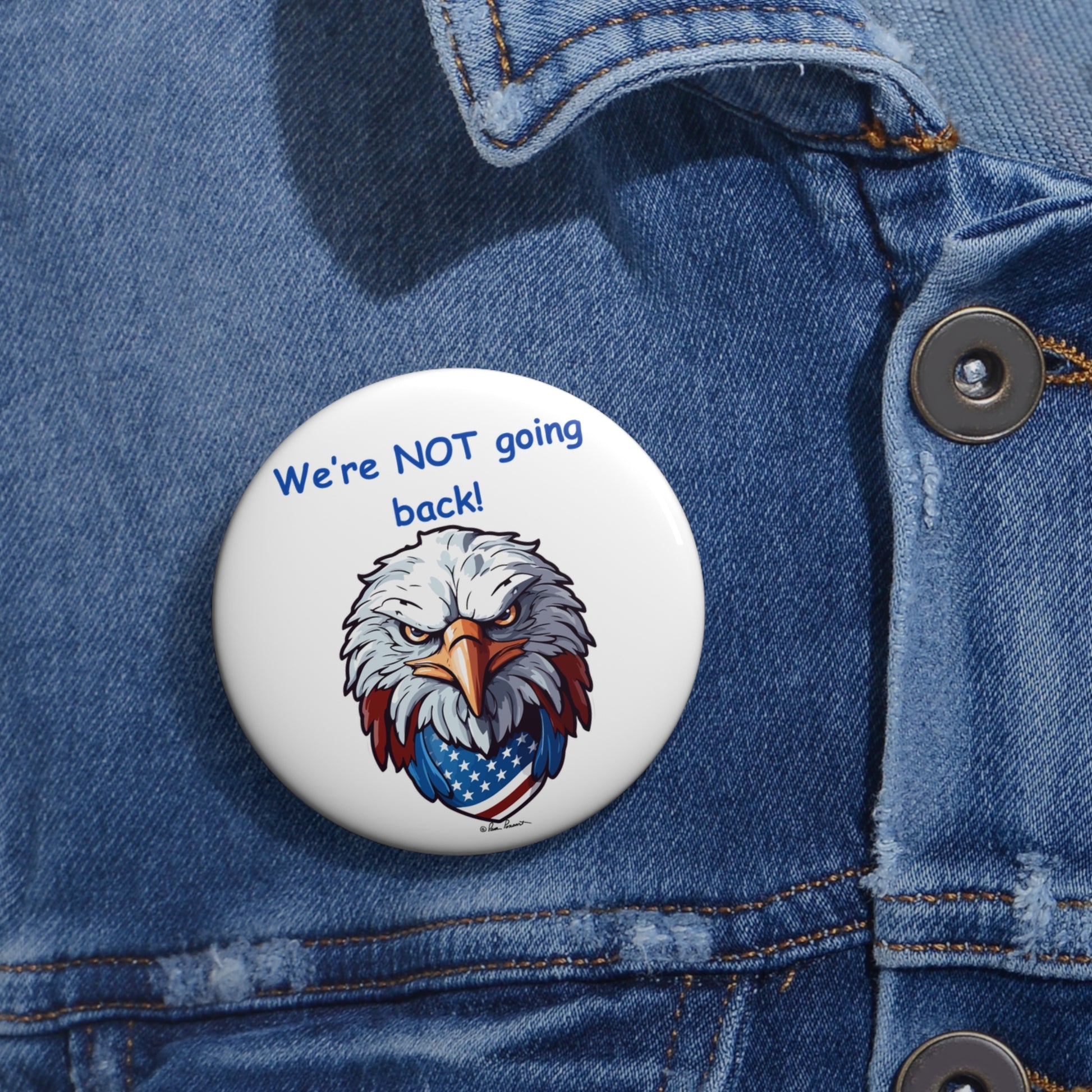 A Printify Not Going Back Button, available in unisex and two sizes, featuring an eagle and U.S. flag design on a denim jacket reads "We're NOT going back!"—a perfect addition for those embracing a patriotic theme.