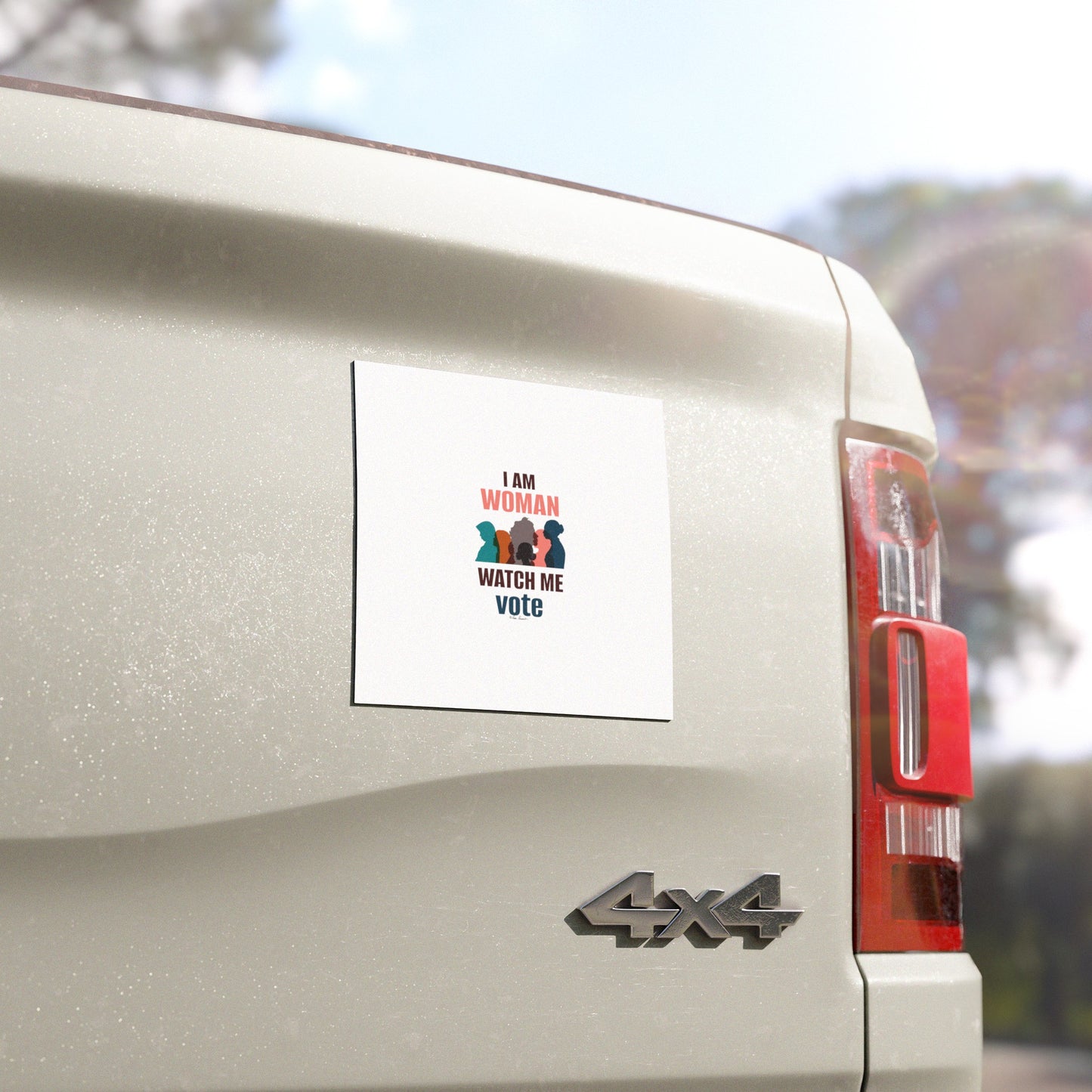 A weatherproof vinyl sticker on the back of a white truck reads "I am woman, watch me vote" with colorful graphics of raised fists, reminiscent of the empowering Voting Womens Car Magnets from Printify.