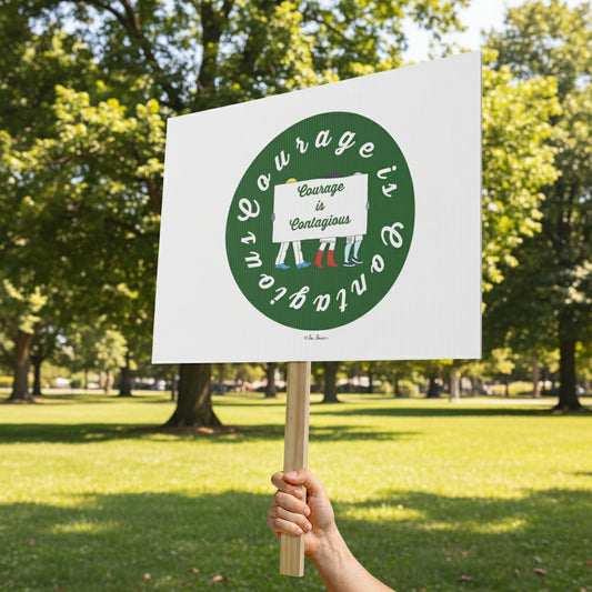A hand holds the Printify Courage-is-Contagious Protest Sign (18" x 24", 1-sided) in a park, featuring "Courage is Contagious" in a green circle with small sock illustrations below.