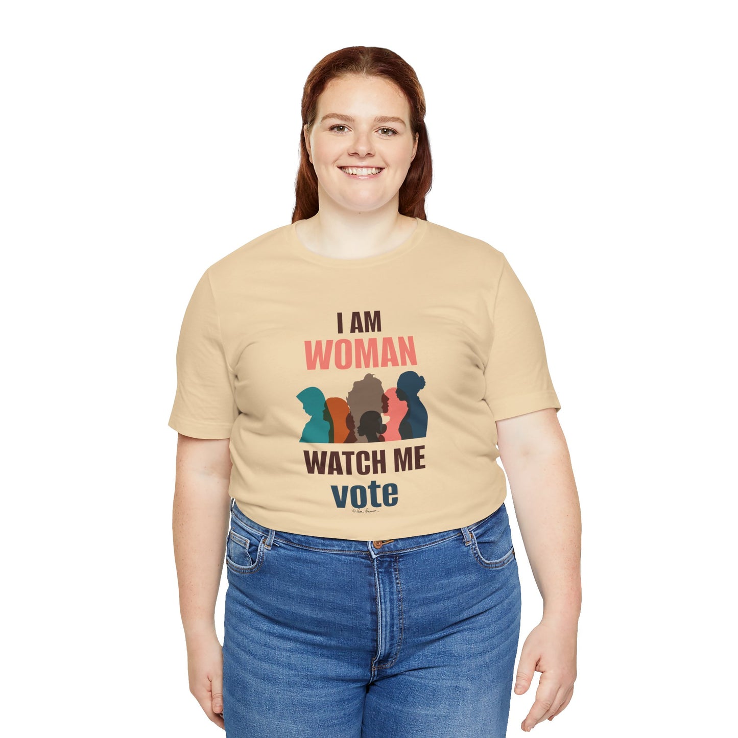A woman in a Printify Voting Women's T-shirt, in a beige Bella + Canvas tee with "i am woman watch me vote" printed on it, and blue jeans, smiling at the camera.