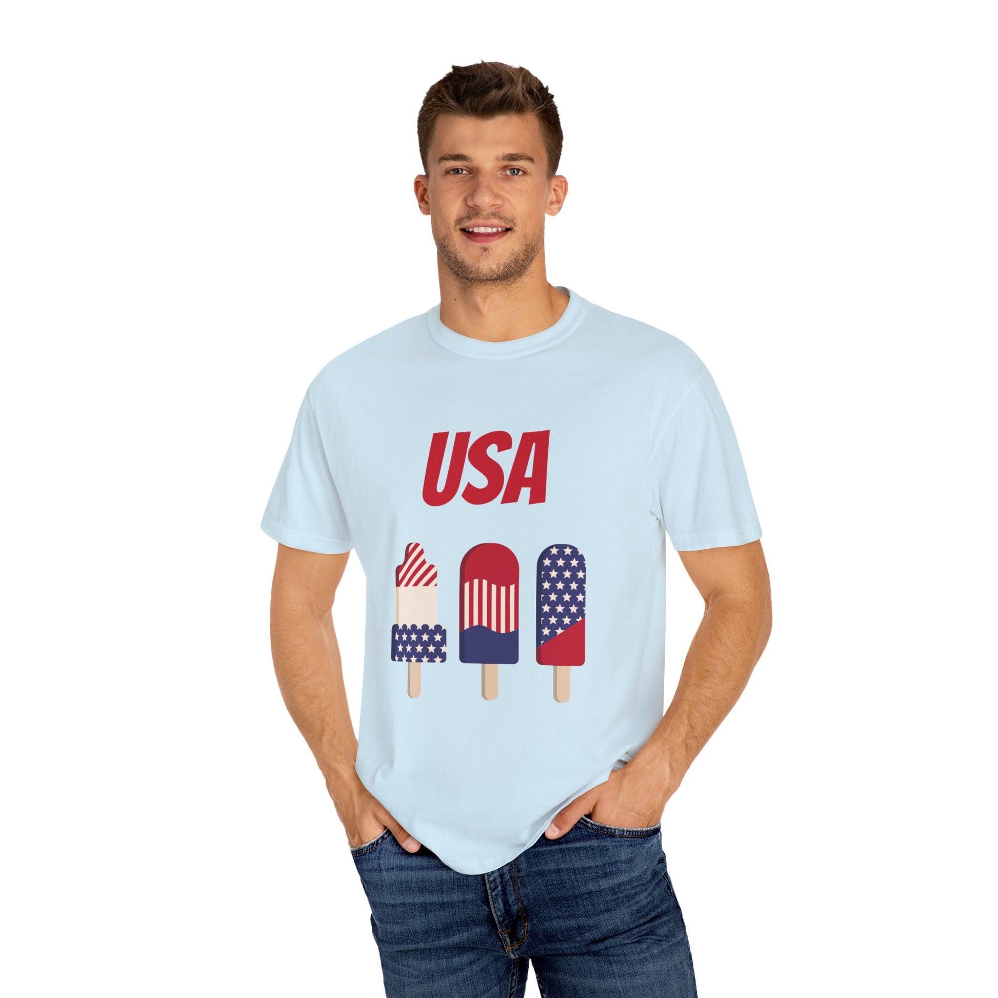 A person wearing a light blue Printify Unisex USA T-shirt: 3 colors; Cotton; Comfort Colors 1717 boasts images of four popsicles decorated in red, white, and blue patterns. Made from 100% ring-spun cotton by Comfort Colors, this shirt offers both style and comfort.