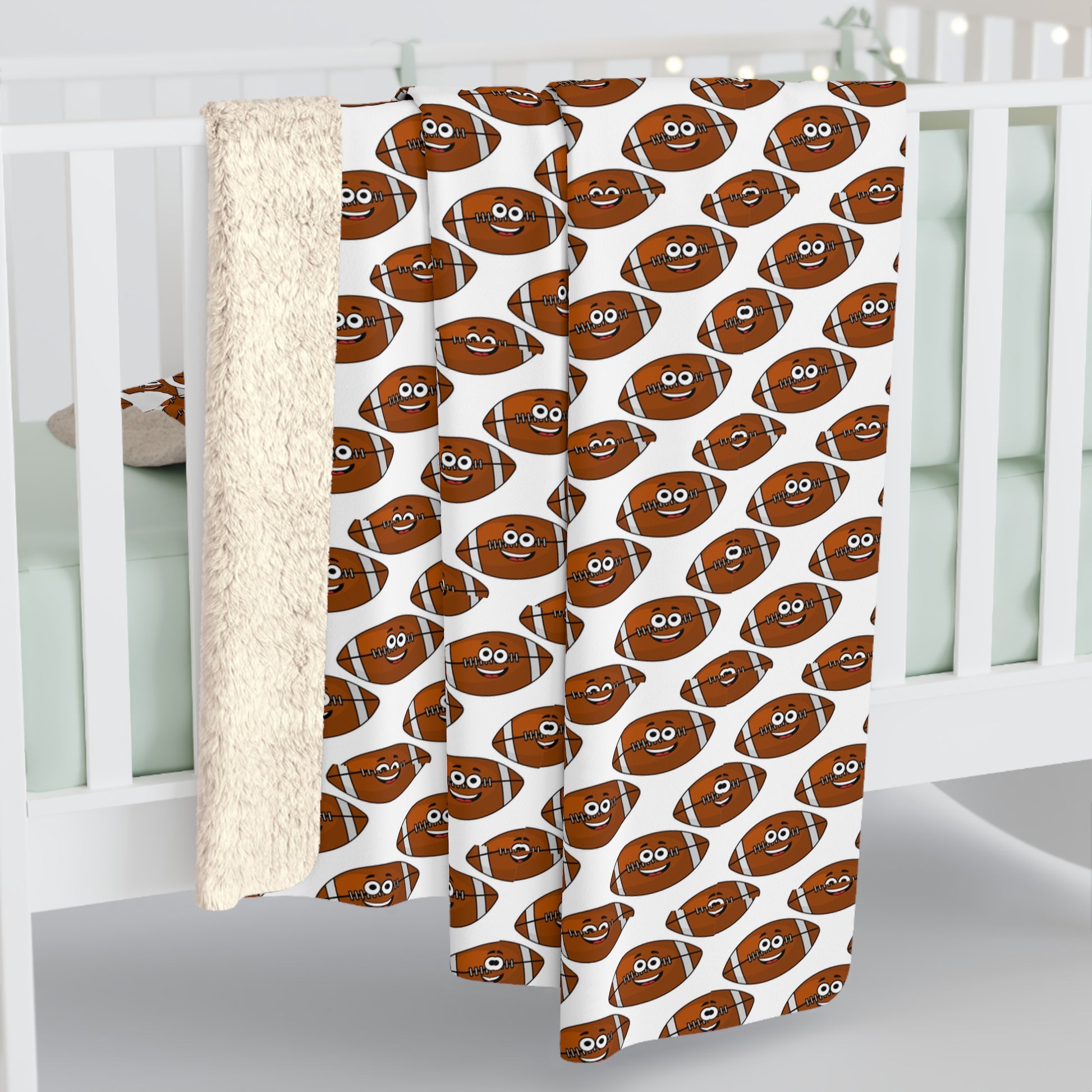 The Happy Football-Faces Blanket by Printify, featuring a fun cartoon football pattern and available in two sizes, is lovingly draped over a white crib with pale green bedding—a perfect delight for young sports enthusiasts. Made from soft Sherpa polyester, it's ideal for cuddling.