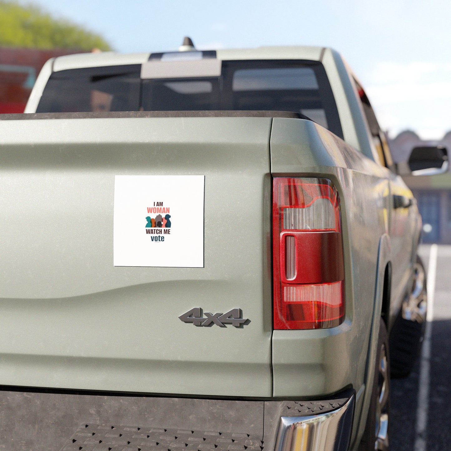 A green 4x4 pickup truck features a weatherproof vinyl bumper sticker from Printify on the tailgate that reads "I AM WOMAN, WATCH ME VOTE" in red and black text.