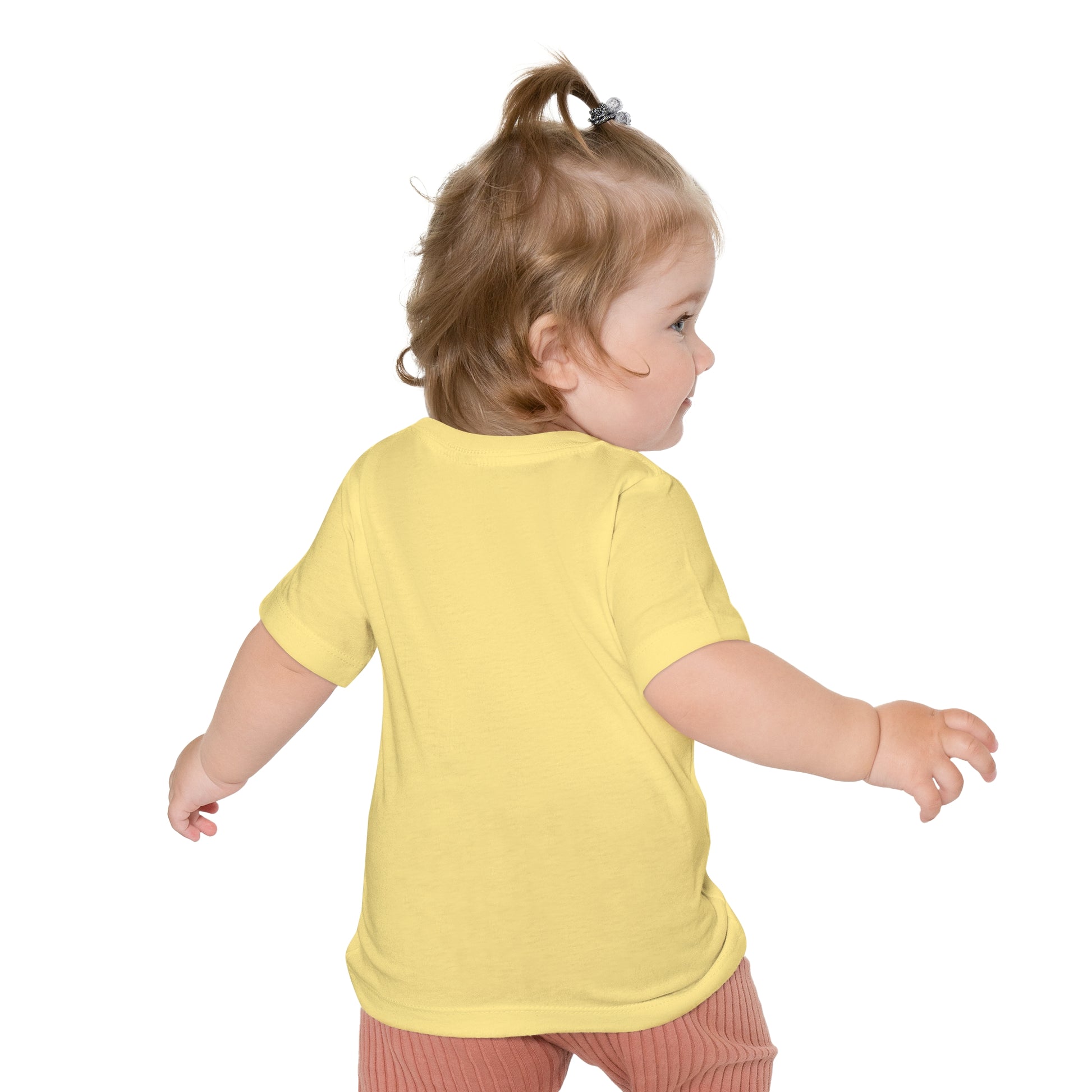 Toddler in a unisex crew neck Printify's Baby's Easter-Gnome T-shirt and red pants looking over shoulder.
