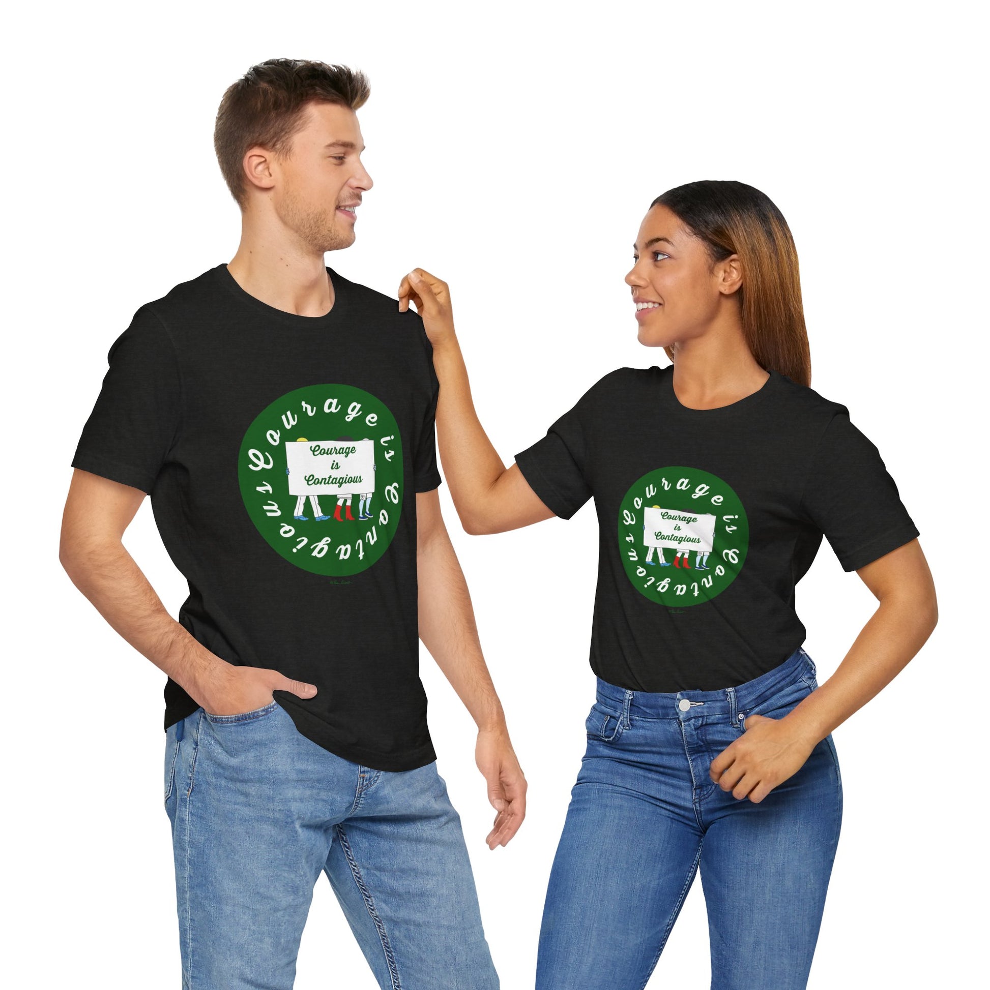 A man and woman smile at each other while wearing matching black Printify Courage Is Contagious T-shirts from Activist Graphics, featuring a green circular logo and text.