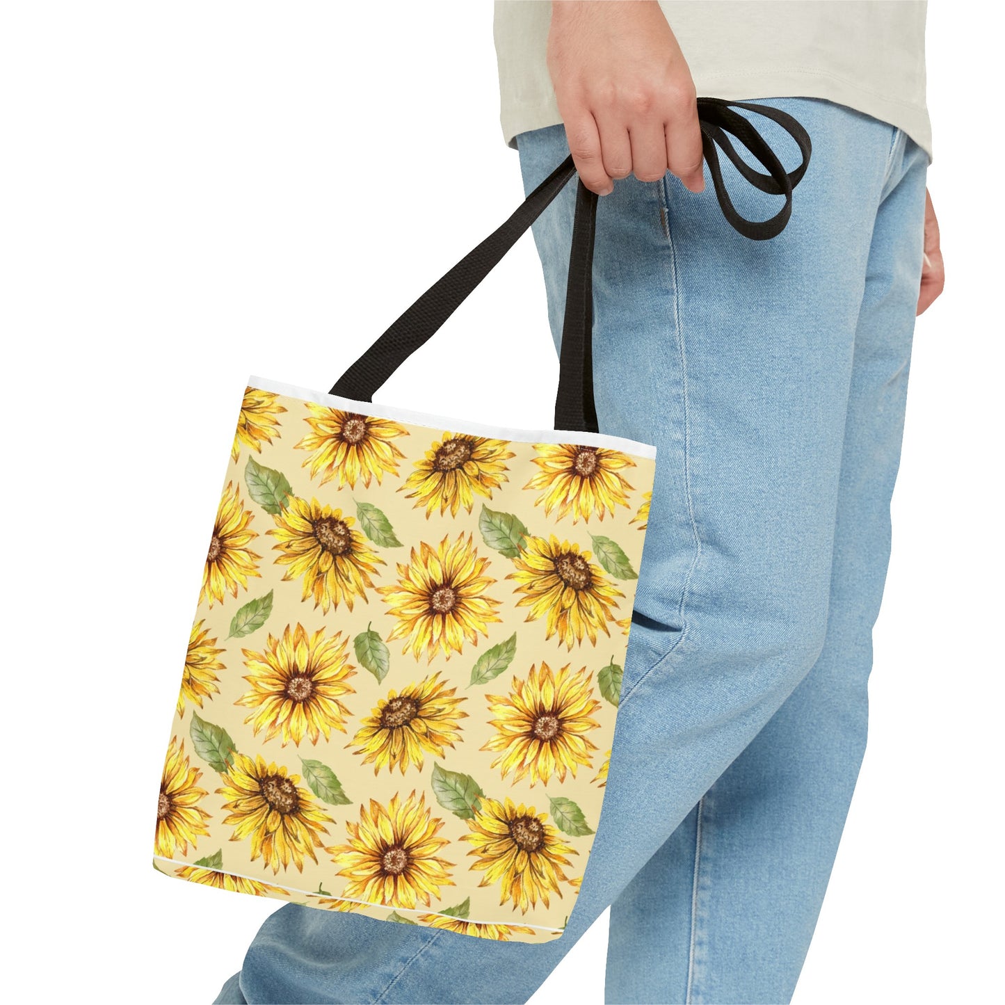 Person holding a Printify Yellow Floral Tote Bag with a sunflower print, showcasing the pattern as they stand.