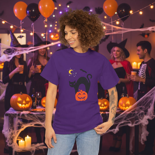 A person wearing the Printify Black Cat Halloween T-shirt in purple stands at a lively Halloween party with festive décor and guests in costumes.