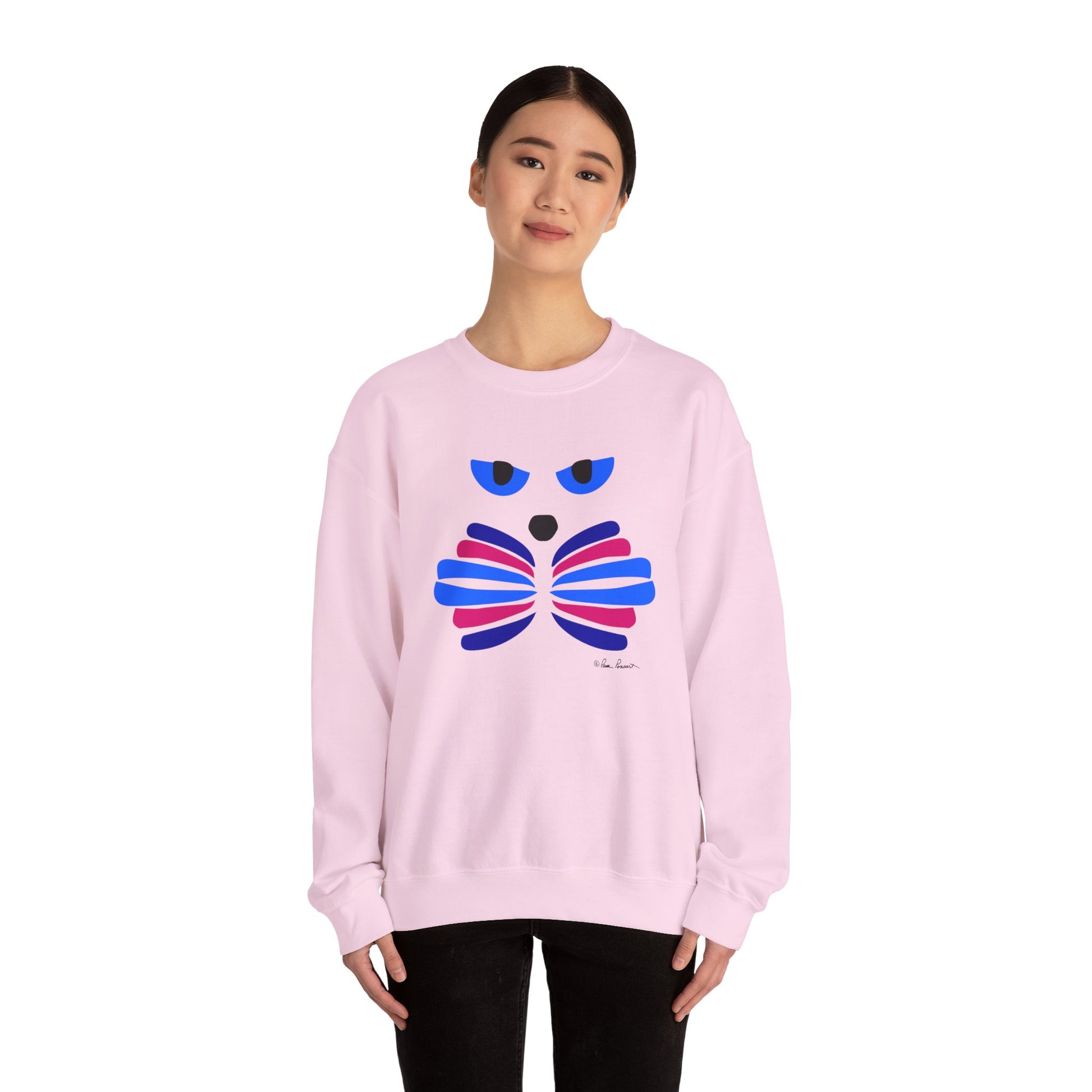 A person wears the Printify Whimsical Cat Graphic Sweatshirt—an artistic, unisex crewneck with a blue, pink, and red cat design—standing against a plain white background.