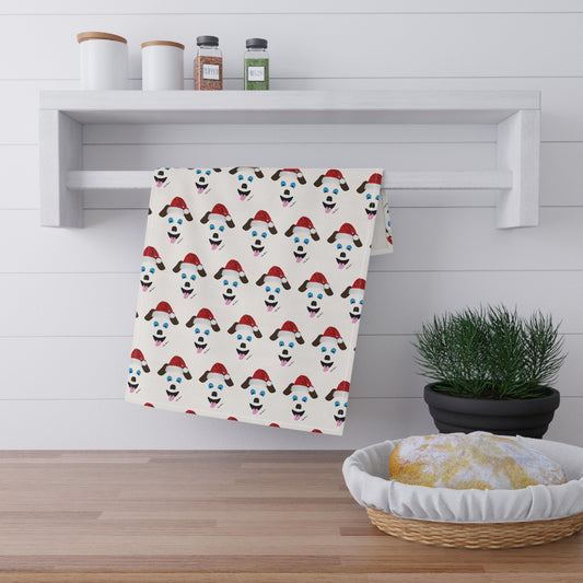 In a cozy kitchen setting, a Printify Festive Santa-Dog Kitchen Towel, measuring 18" x 30" and featuring joyful polar bears sporting Santa hats, enhances the holiday atmosphere. A small potted plant and round dish are nestled on the wooden countertop below a shelf that holds two jars—ideal for holiday gatherings.