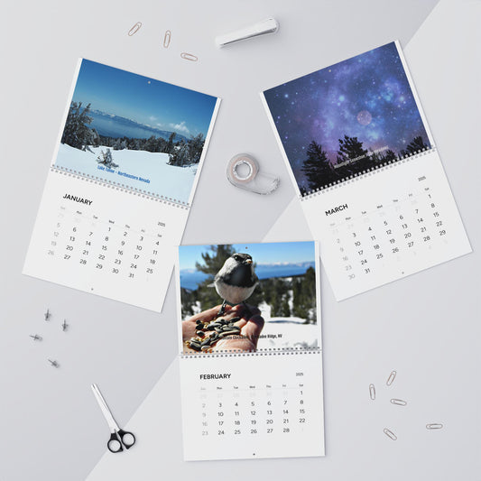 The Printify Minimalist 2025 Wall Calendar showcases a snowy landscape, a bird, and a starry night sky for the first three months. Surrounded by office supplies, this photographic calendar creates an inspirational atmosphere.