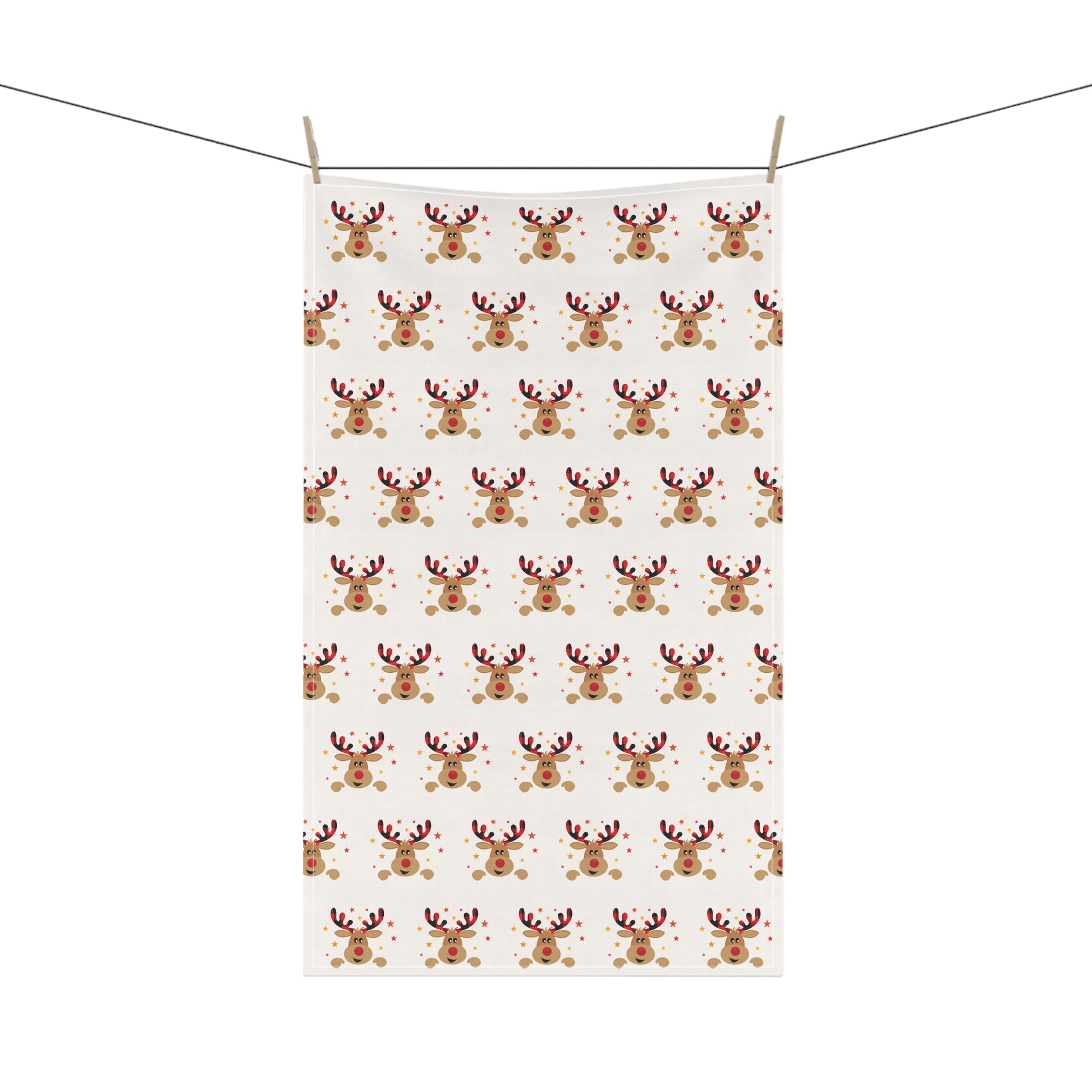 A Festive Reindeer Tea Towel from Printify, featuring a repeating pattern of joyful holiday reindeer faces, hangs beautifully on a clothesline, embodying the festive spirit.