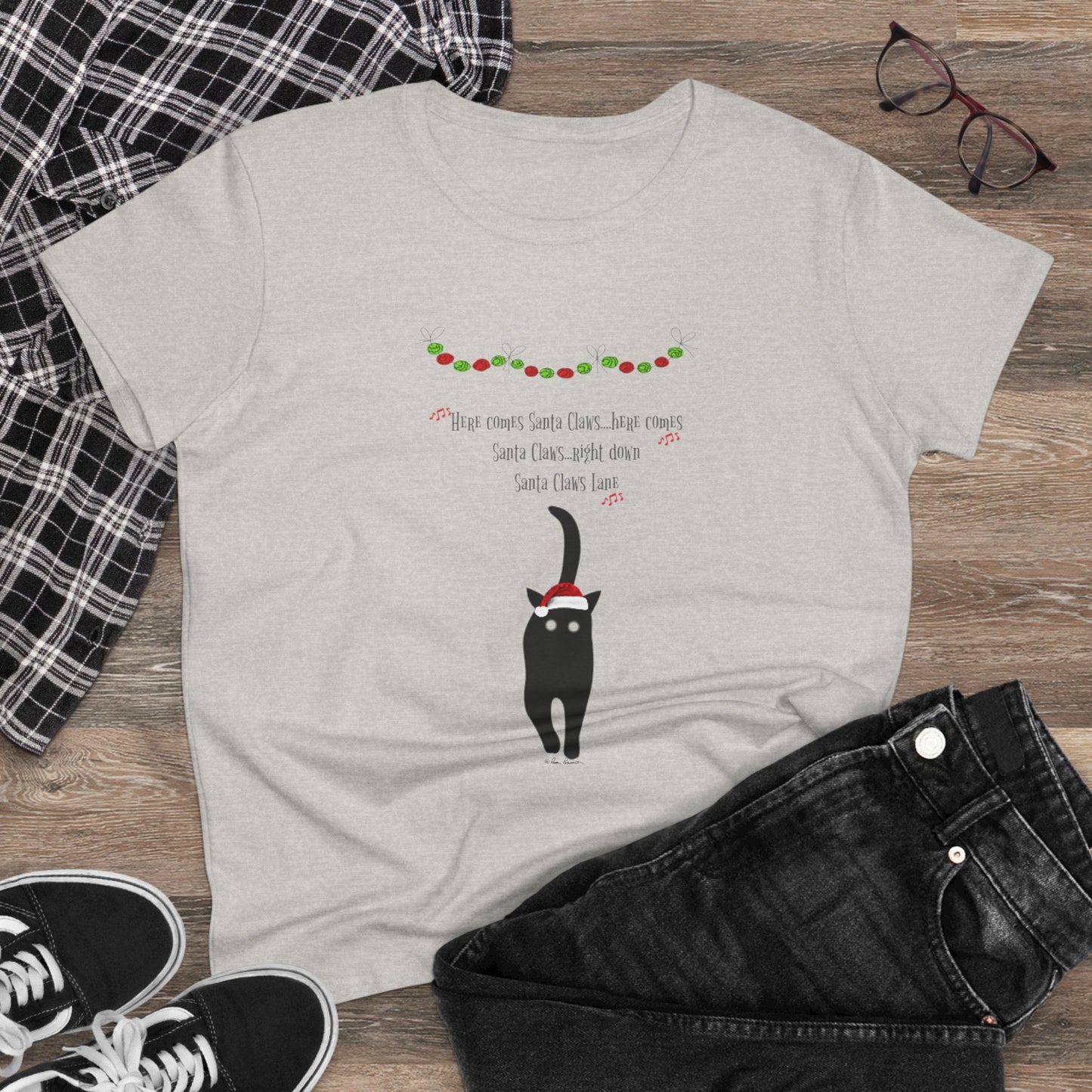 The Santa Claws T-shirt by Printify is a festive gray cotton top for women, featuring a black cat in a Santa hat with holiday lights and "Here comes Santa Claus" text—perfectly styled with jeans and sneakers for a cheerful holiday look.